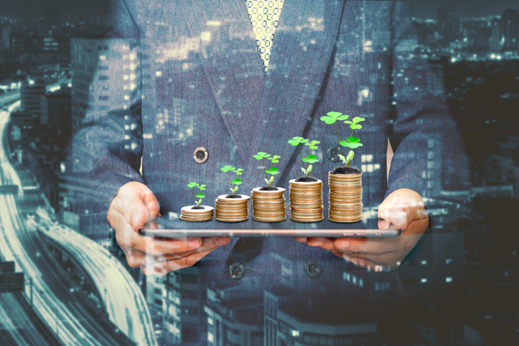 Businessman holding a tablet with coins stack and tree,Lucky economic growth concept